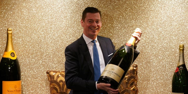 Man holds what appears to be a Salmanazar of champagne
