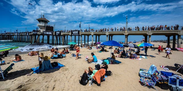 Surfing fans watch the action from the beach and on the Huntington Beach Pier during opening day of the US Open of Surfing in Huntington Beach, California, Saturday, July 30, 2022. 