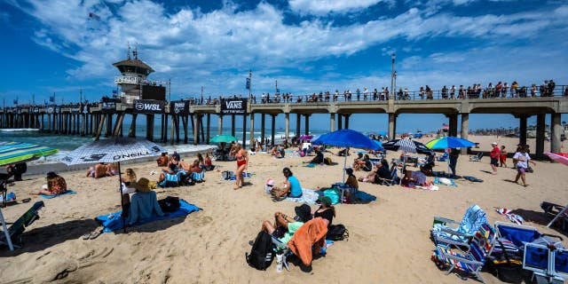 Surfing fans watch the action from the beach and on the Huntington Beach Pier during opening day of the US Open of Surfing in Huntington Beach, California, Saturday, July 30, 2022.