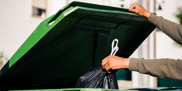 Man takes out garbage and puts in trash bin