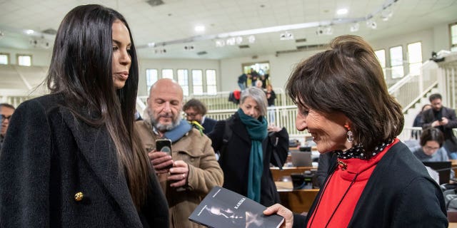 Karima El Mahroug, aka Ruby Rubacuori, one of the girls who attended the infamous Bunga Bunga parties, presents her book to prosecutor Tiziana Siciliano, right, in Italy, on Feb. 15, 2023. 