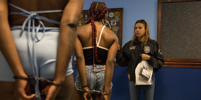An LAPD officer (right) speaks to two recently arrested women at the 77th LAPD headquarters.