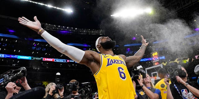 El alero de Los Angeles Lakers, LeBron James, lanza un poco de polvo al aire antes del partido de baloncesto de la NBA del equipo contra el Oklahoma City Thunder el martes, 7 de febrero de 2023, en Los Ángeles.