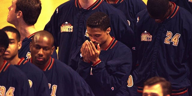 El armador de los Denver Nuggets, Mahmoud Abdul-Rauf, ora durante el canto del himno nacional antes de un partido de los Nuggets contra los Chicago Bulls en el United Center de Chicago el 15 de marzo de 1996.