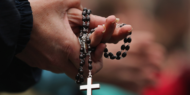Woman holds rosary in Vatican City.
