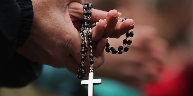 Woman holds rosary in Vatican City.