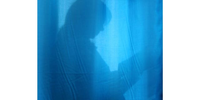 A pregnant woman is seen through the curtain at a maternity hospital in the Ukrainian capital Kyiv, on Oct. 31, 2004.