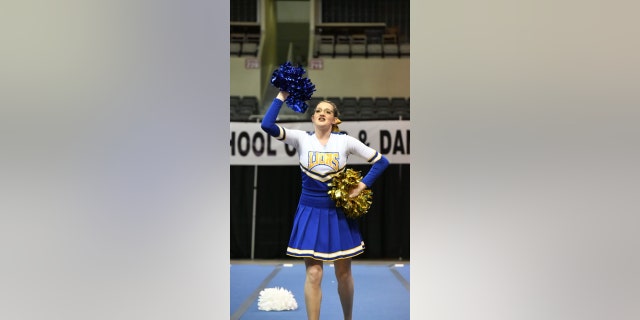 Katrina switches poms to gold and blue colors during her solo cheer routine on Feb. 17 after her small squad of team members couldn't attend.