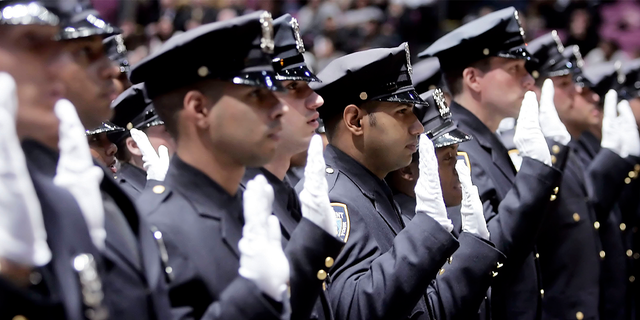 Members of a New York Police Department class of cadets raise their right hands as they take their oath during their graduation from the NYPD Police Academy.