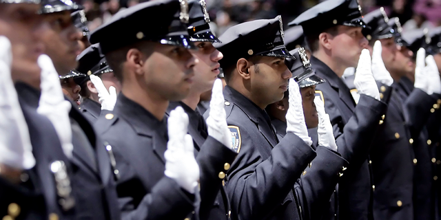 New York Police Department recruits raise their right hands as they take their oath during their graduation from the NYPD Police Academy.