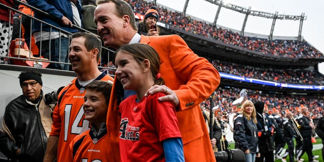 Former Denver Broncos quarterback Peyton Manning stands with his children, Marshall and Mosley, and former teammate Brandon Stokley at Empower Field at Mile High on Oct. 31, 2021.