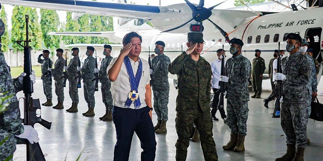 Philippine President Ferdinand Marcos Jr., left, walks beside honor guards during his visit at an airbase on Feb. 27, 2023. 