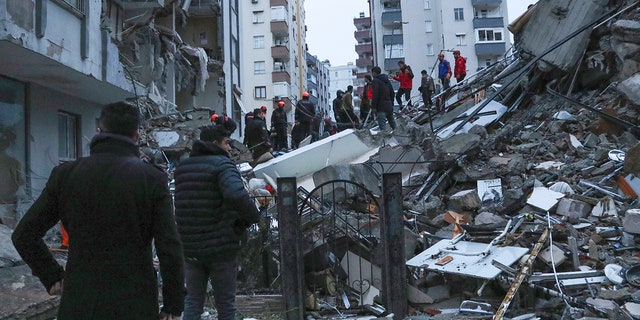 People and rescuers try to reach people trapped inside collapsed buildings in Adana, Turkey, Monday, Feb. 6, 2023.  A powerful earthquake has toppled several buildings in southeast Turkey and Syria, and many casualties are feared.