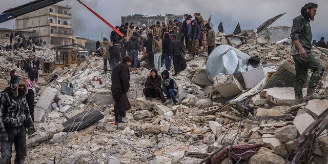 Rescue workers and civilians conduct search and rescue operations following a magnitude 7.8 earthquake that hit Syria. 