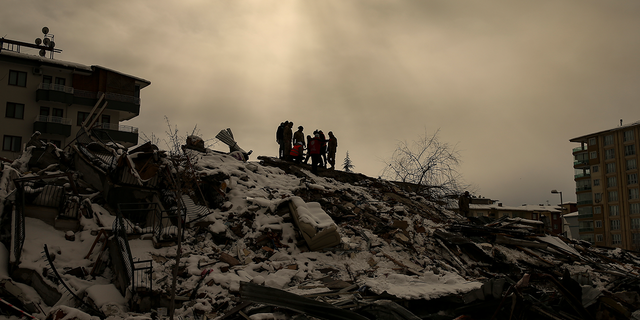 People try to reach people trapped under the debris of a collapsed building in Malatya, Turkey, Tuesday, Feb. 7, 2023.