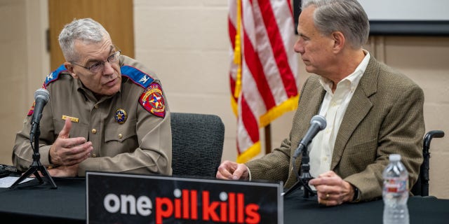 Texas Department of Public Safety Director Steve McCraw, left, speaks with Gov. Greg Abbott at a news conference on Oct. 17, 2022, in Beaumont, Texas.