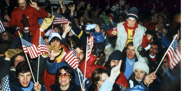 U.S. ice hockey fans wave national flags as they celebrate the United States' upset victory over the Soviet Union (4-3) in the Olympic semifinal match on Feb. 22, 1980, in Lake Placid at the Winter Olympic Games. The USA advanced to the final, where they played Finland for the gold medal.