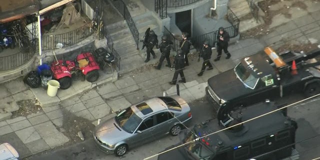 Philadelphia police officers at the scene where an officer was shot Wednesday during a traffic stop. Two suspects have been arrested and a third was being sought. 