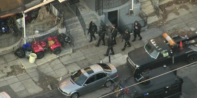 Philadelphia police officers at the scene where an officer was shot Wednesday during a traffic stop. Two suspects have been arrested and a third was being sought.