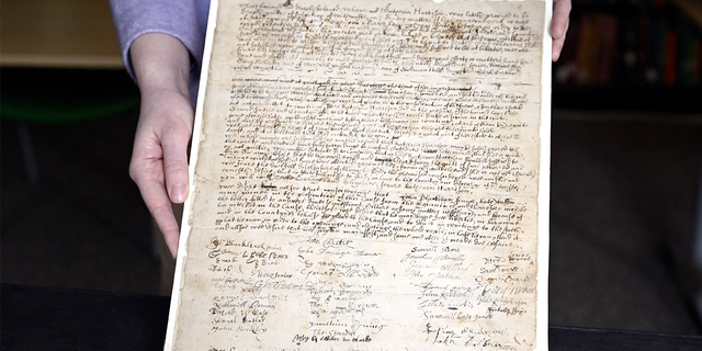 La asociada de colecciones de la Sociedad Histórica de Connecticut, Julia Morrow, muestra una carta de queja original que data de 1669 contra Katherine Harrison, el martes 31 de enero de 2023, en Hartford, Connecticut. Harrison, de Wethersfield, Connecticut, fue juzgado varias veces por brujería.