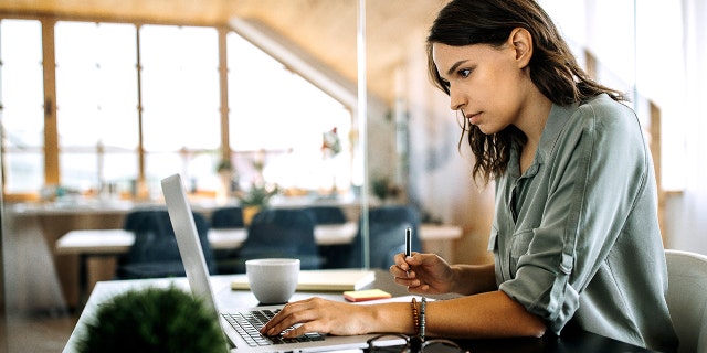 Hardworking Young Woman Writing notes And Using Laptop