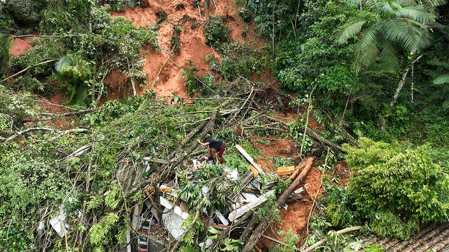 Debris on the side of a hill with a man climbing through.