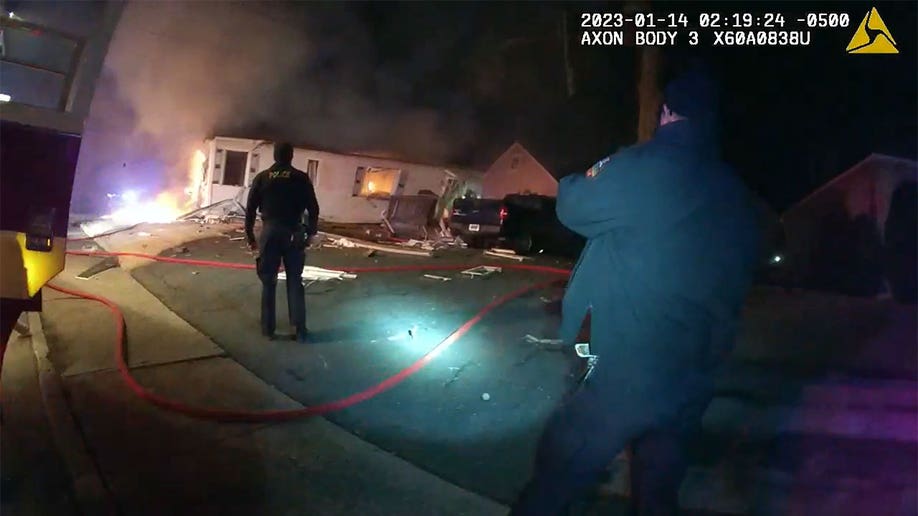 Law enforcement standing next to a house after it exploded.