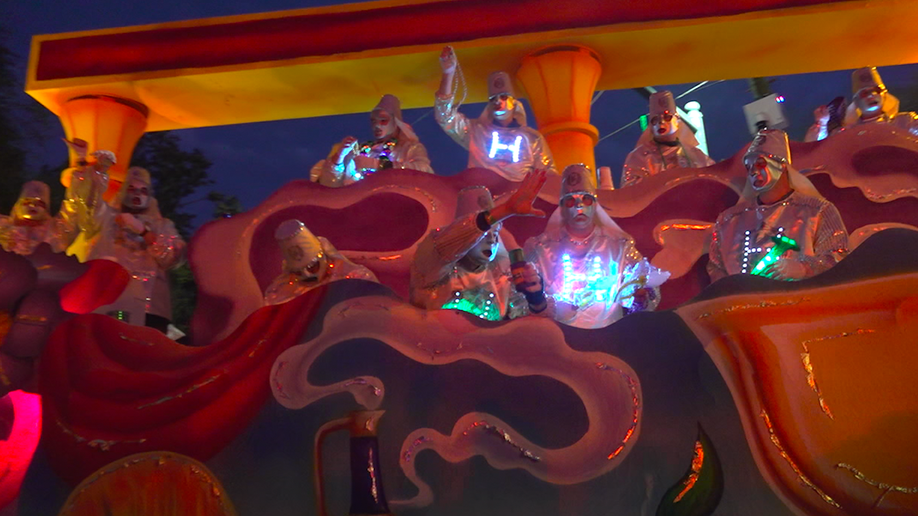 Mardi gras float with people in costume throwing beads on board