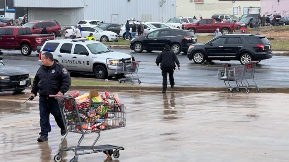 A Travis County Constable stand next to a grocery cart full of spoiled food