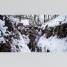 Men in military gear walk through snow.
