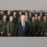Vladimir Putin stands in front of a group of soldiers.