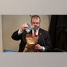 A man examines evidence on the witness stand inside a courtroom.