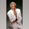 Burt Bacharach posing for a picture with a green backdrop