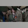 A man wearing military gear kisses a woman.