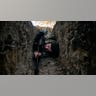 A man wearing military gear hides in a trench.