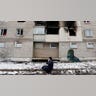 A woman weeps outside of a destroyed apartment complex.