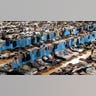 Hundreds of people sleep on cots inside of an arena.