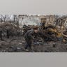 A man walks past a destroyed building.