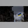 The Ukrainian flag flies among destruction.