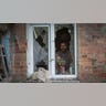 A man places flowers in a broken windowsill.