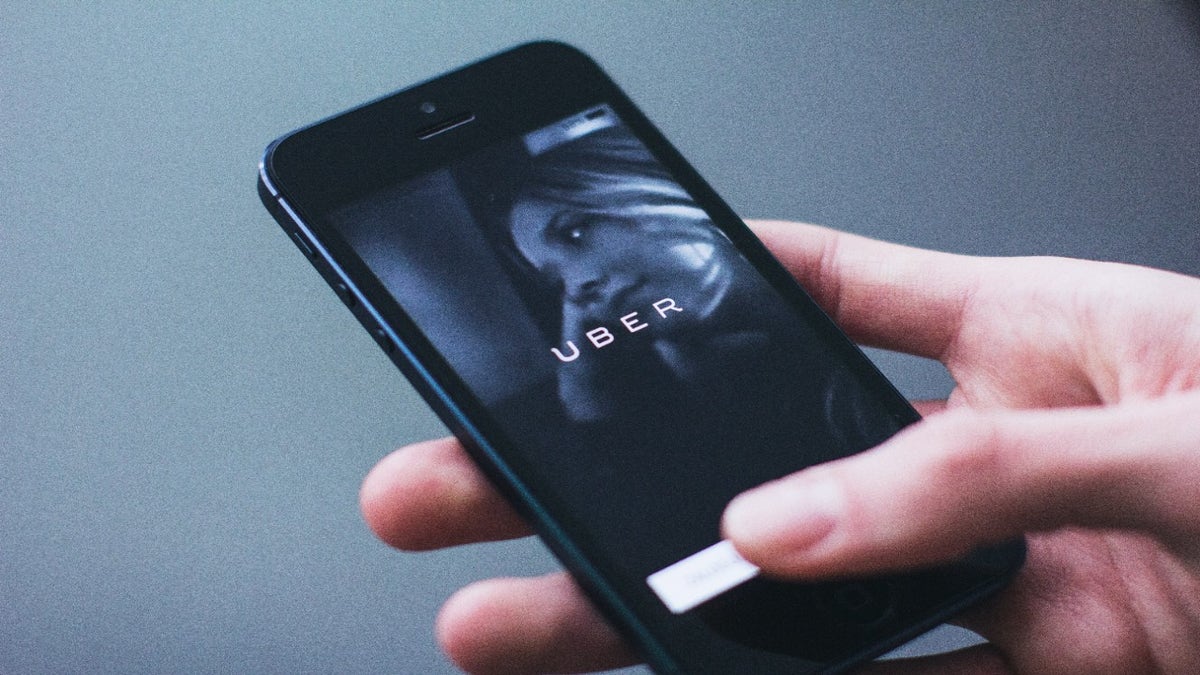 Man holds phone with uber on screen