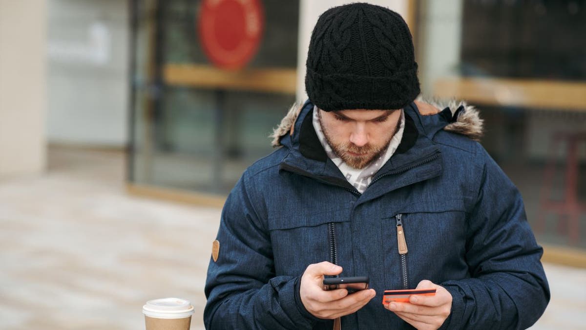 Man with winter outerwear looks down at his phone