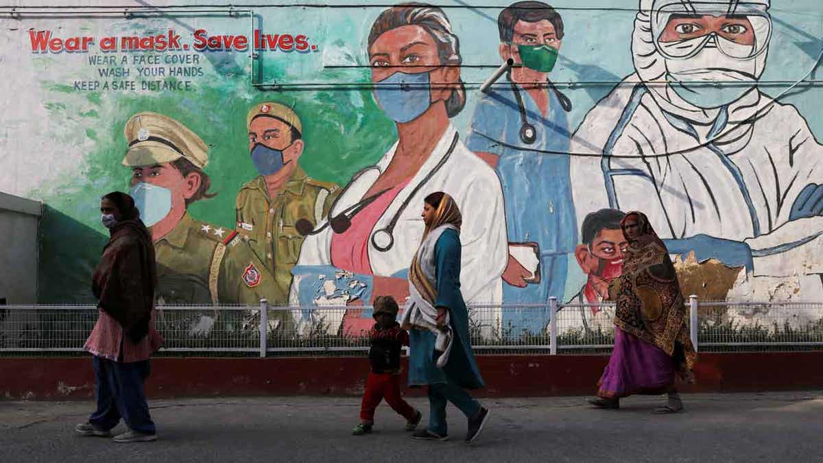 Women walk past a graffiti 