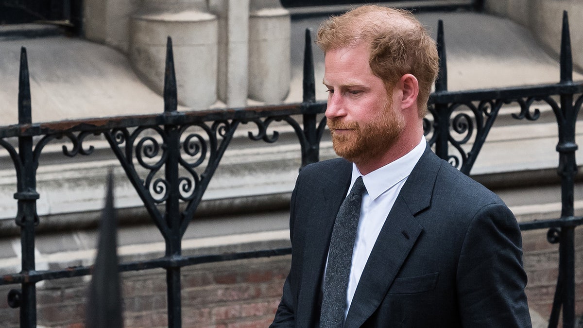 Prince Harry looking glum wearing a dark suit and tie