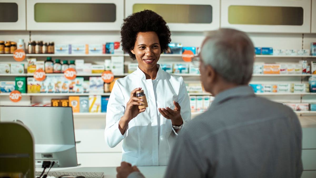 Pharmacist speaks with patient at pharmacy counter