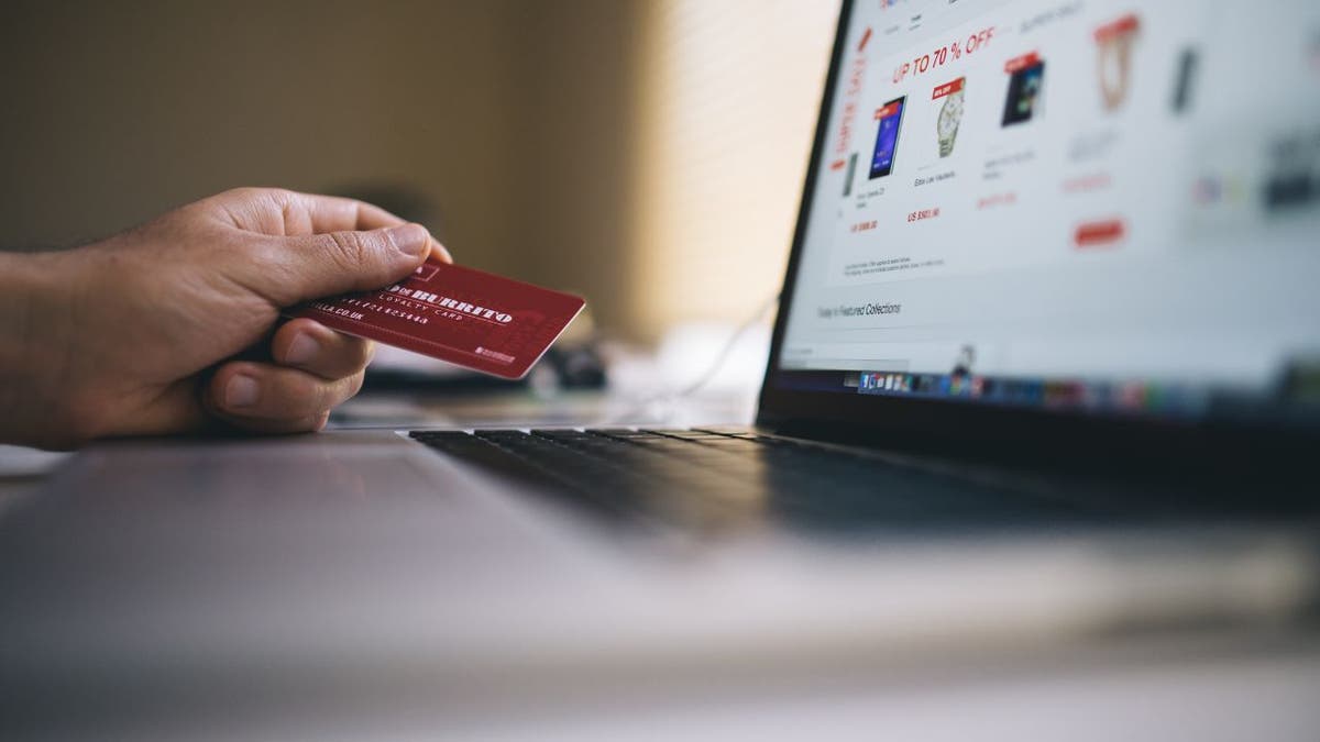 Person holds credit card as they buy items online