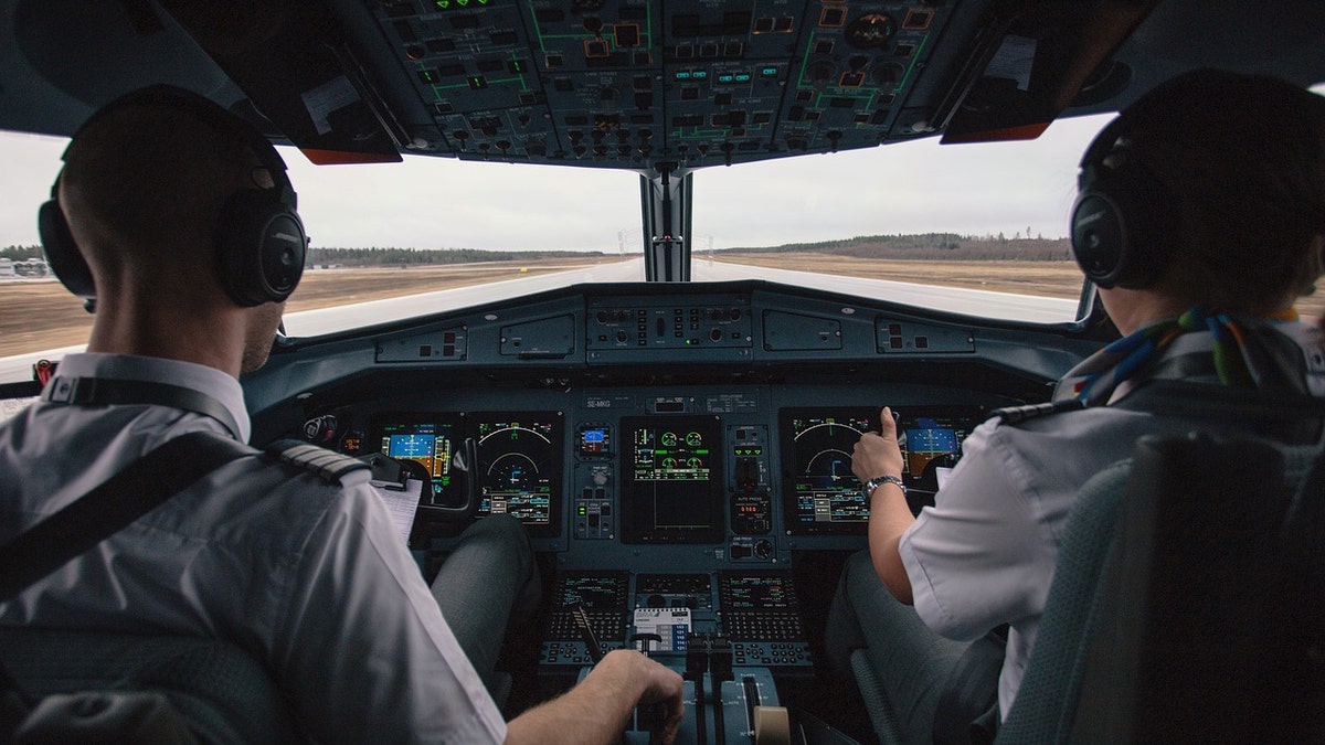 Pilots sit in cockpit with headsets on