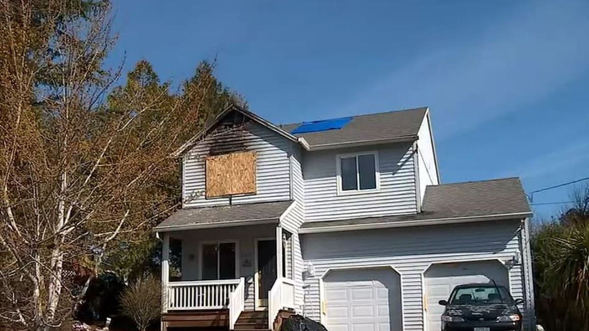 Oregon house shown after fire, with plywood over upstairs window