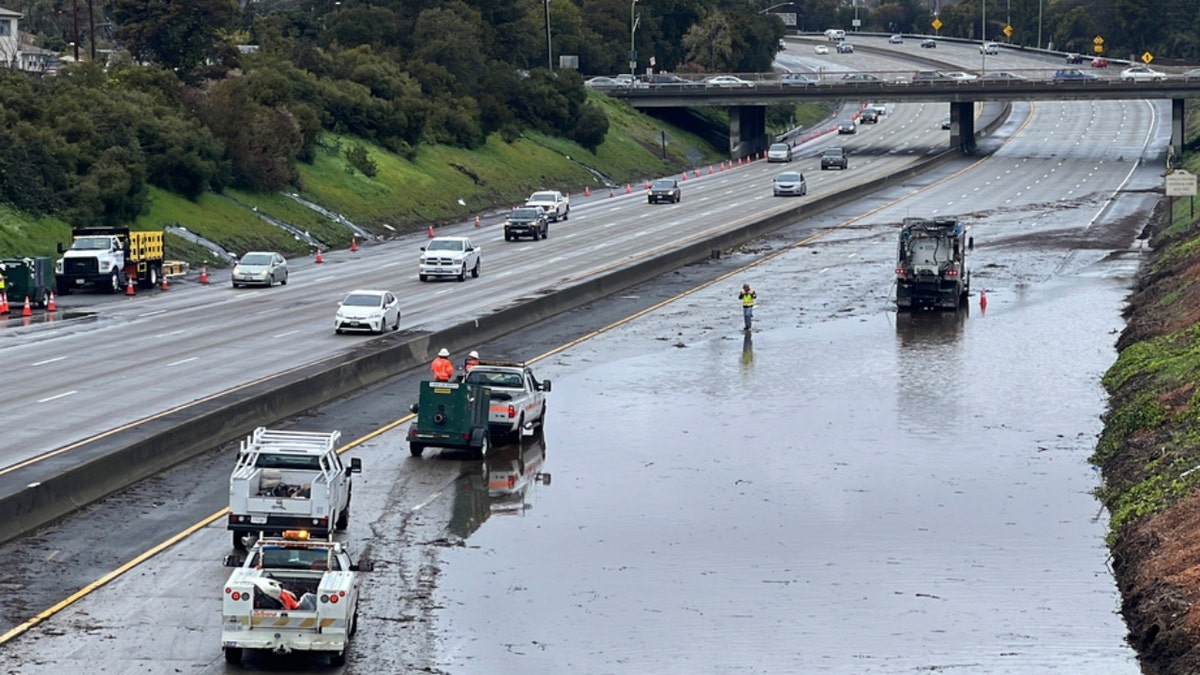 Caltrans crews work by a flooded section of Interstate 580