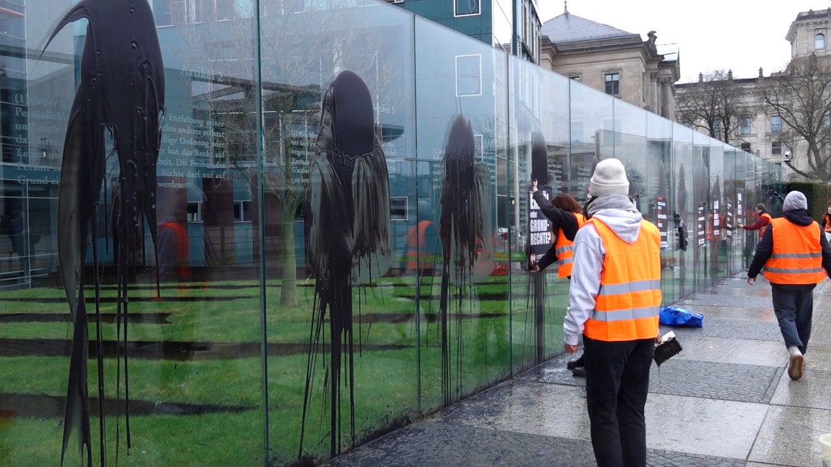 Climate activists of the "Last Generation" attend a protest at the Jakob-Kaiser-Building in Berlin, Germany, Saturday, March 4, 2023. Climate activists on Saturday splashed a dark liquid over an artwork near the German parliament building engraved with key articles from the country's constitution, drawing condemnation from the speaker of parliament and other lawmakers.